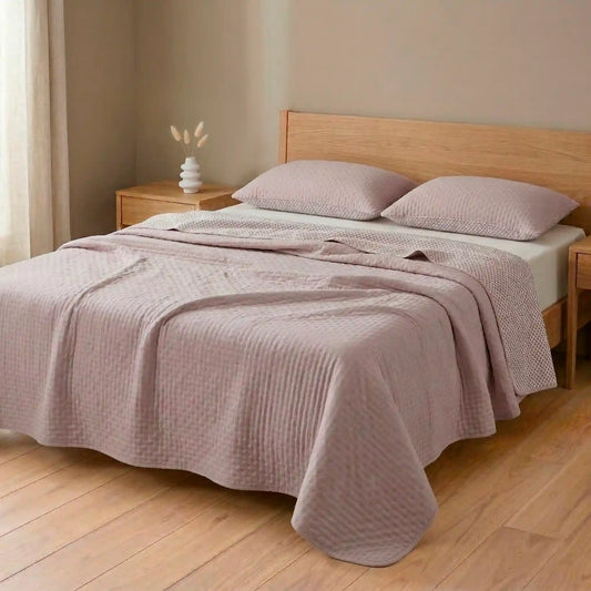 Cama decorada con colcha bouti de verano en tono malva pastel