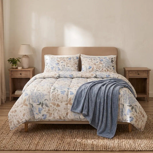 Dormitorio acogedor con edredón floral azul y una manta texturizada en tono azul grisáceo doblada a los pies de la cama para mayor calidez.