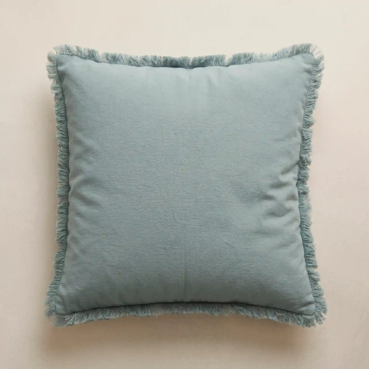 Funda de cojín azul claro 45x45cm de 100% algodón con detalles de flecos de Oma Home. Diseño sereno y luminoso para sofá.