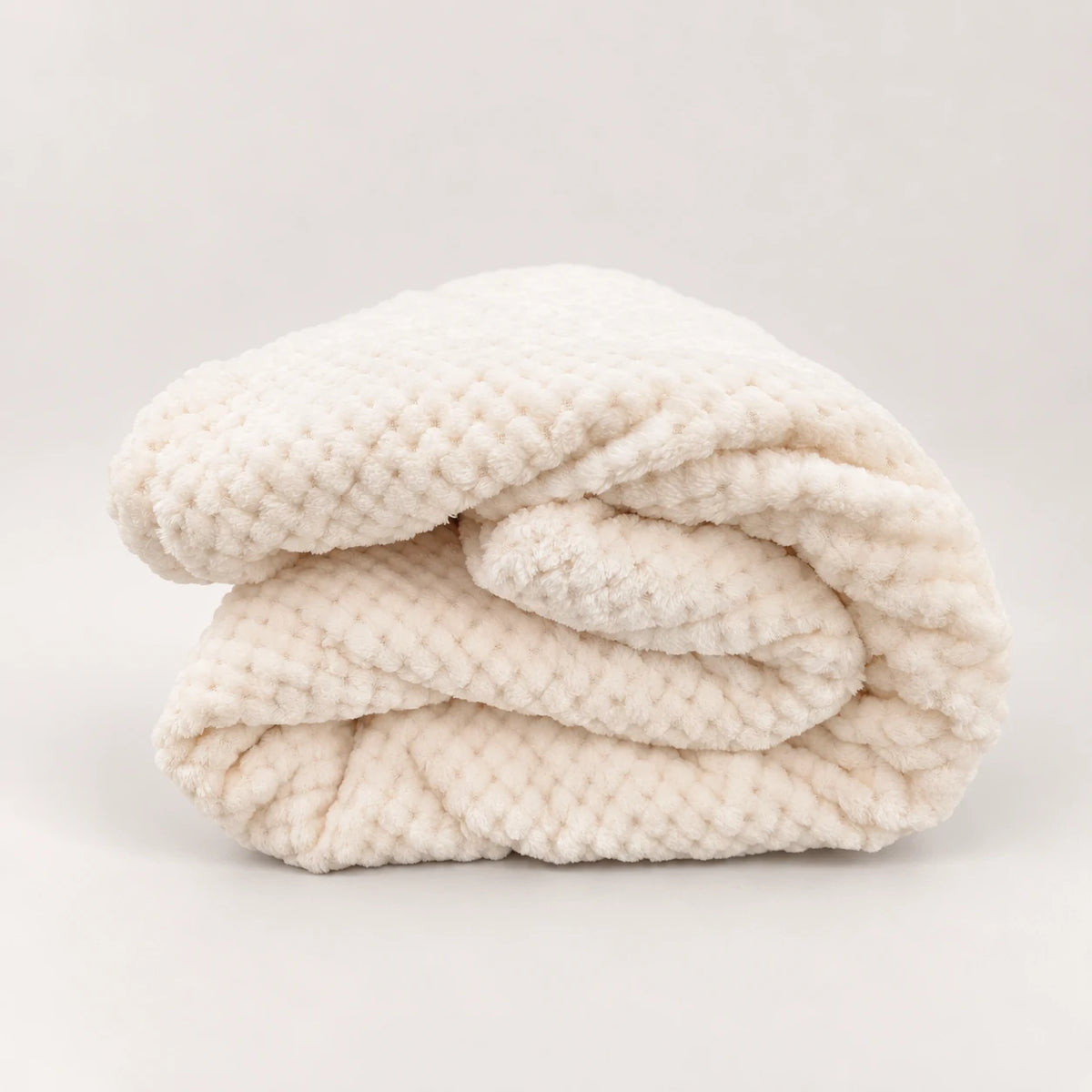 Detalle de perfil de la manta polar fina blanco roto destacando su gramaje ligero y plegado compacto.